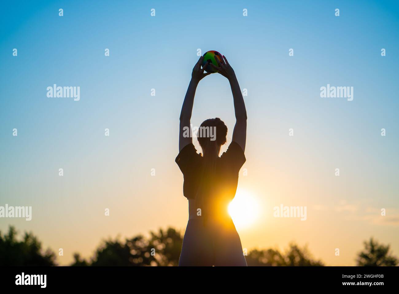 Silhouette einer jungen Frau, die Yoga mit einem Ball vor dem Hintergrund der aufgehenden Sonne am frühen Morgen macht glückliche Person Silhouette gegen Beauti Stockfoto