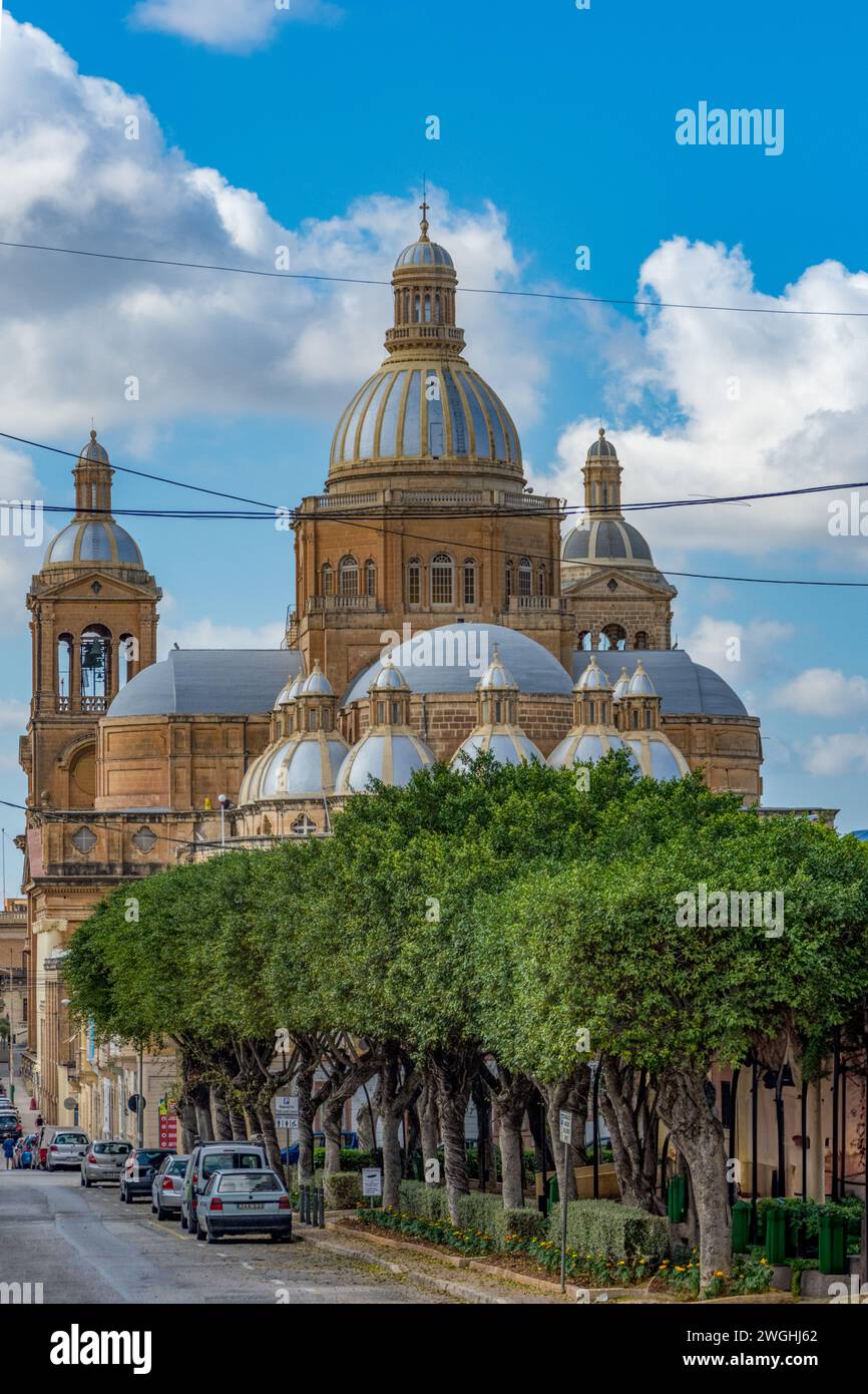 Paola, Malta - 20. Oktober 2019: Die von Bäumen gesäumte Straße führt zur Basilika Christi des Königs, der Pfarrkirche von Paola. Stockfoto