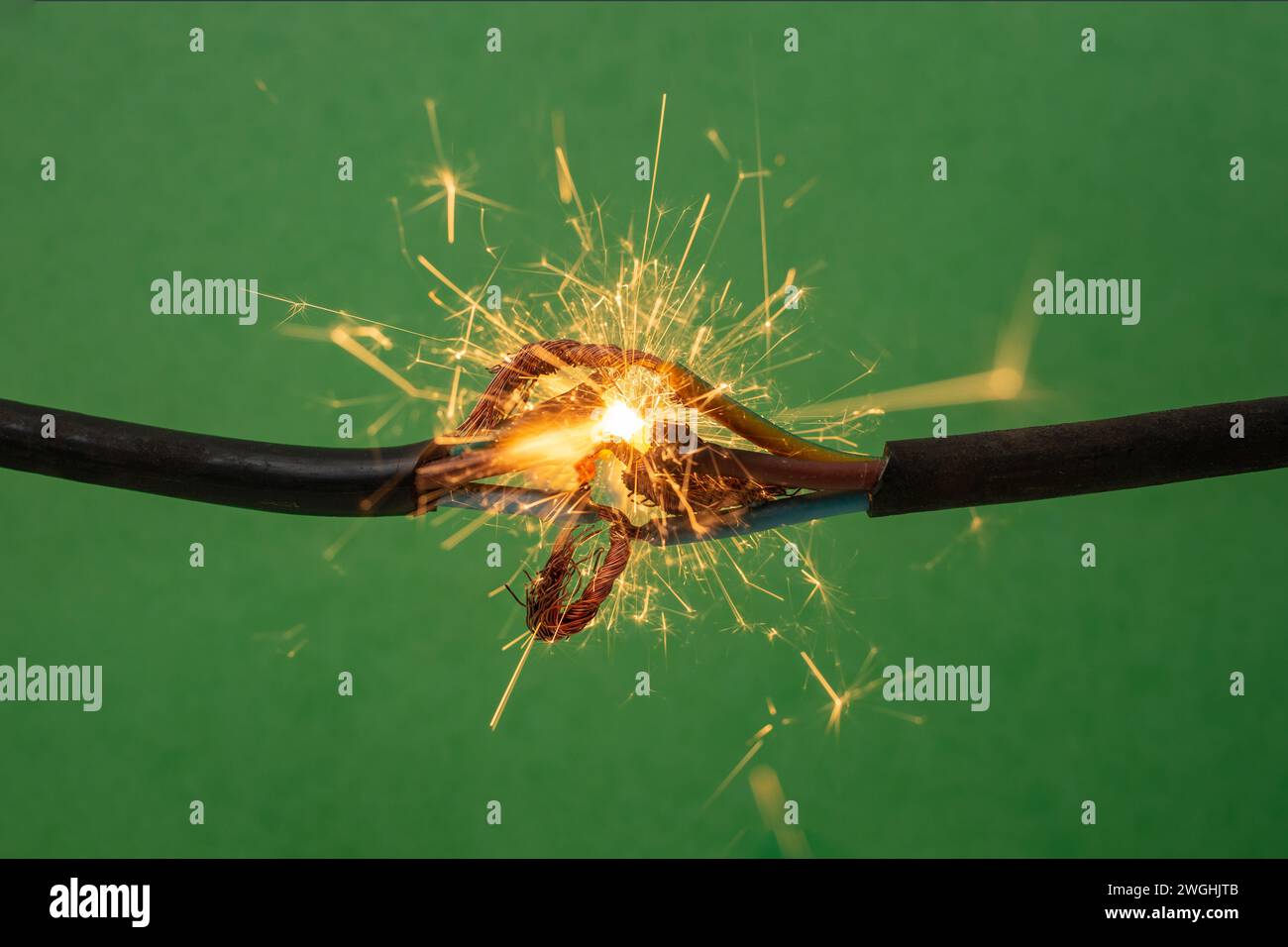 Funkenexplosion zwischen elektrischen Kabeln, auf grünem Hintergrund, Brandschutzkonzept Stockfoto