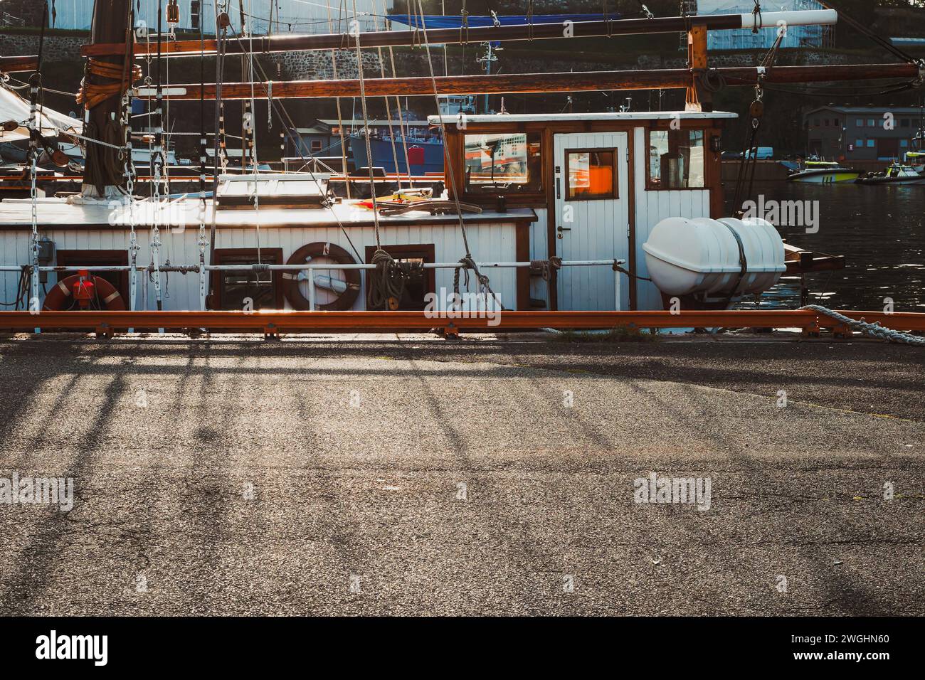 Aus nächster Nähe auf ein hölzernes Segelboot-Cockpit, das in einem Stadthafen bei Hintergrundbeleuchtung vertäut ist Stockfoto