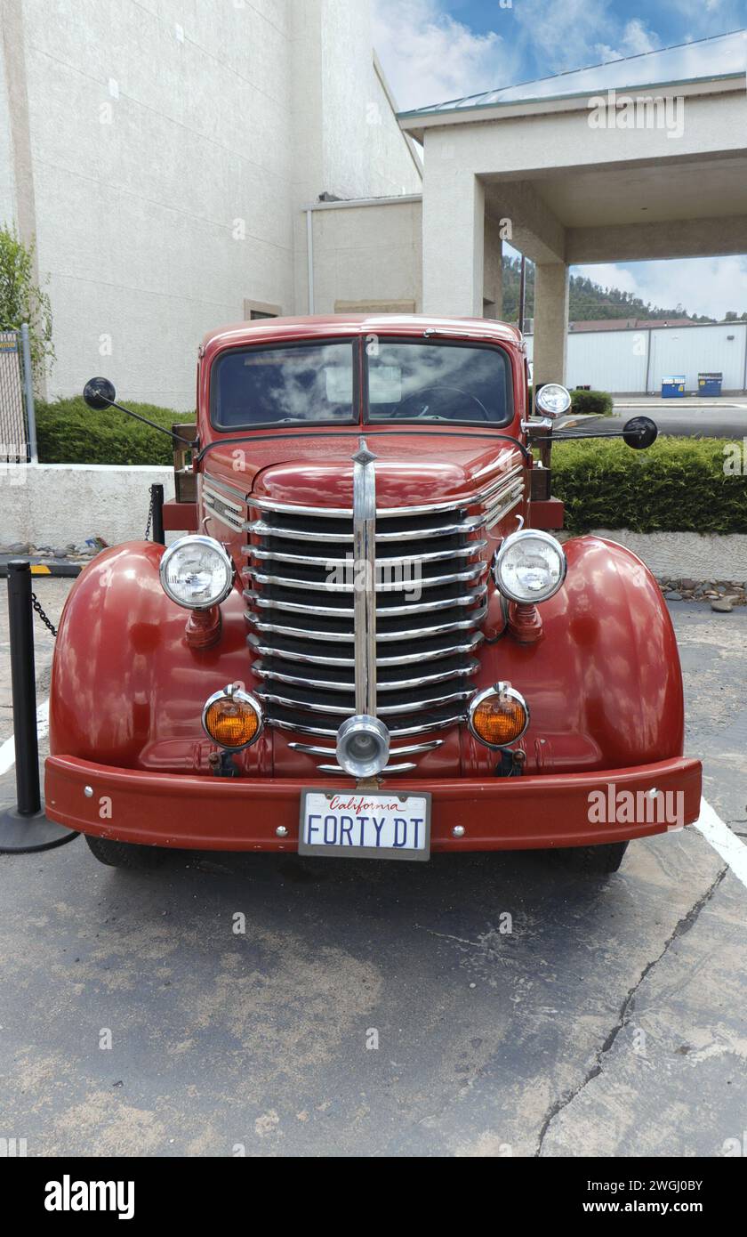 Roter Diamond T-Tieflader aus den 1940er Jahren mit Chromgrill und Scheinwerfern, die in einem Stadtgebiet unter teilweise bewölktem Himmel geparkt sind. Stockfoto