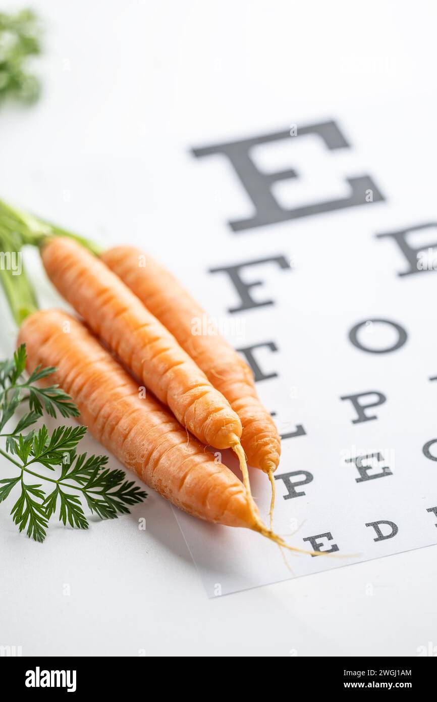 Frische Karotten als Vitamin-A-Quelle auf der Augentestkarte. Stockfoto