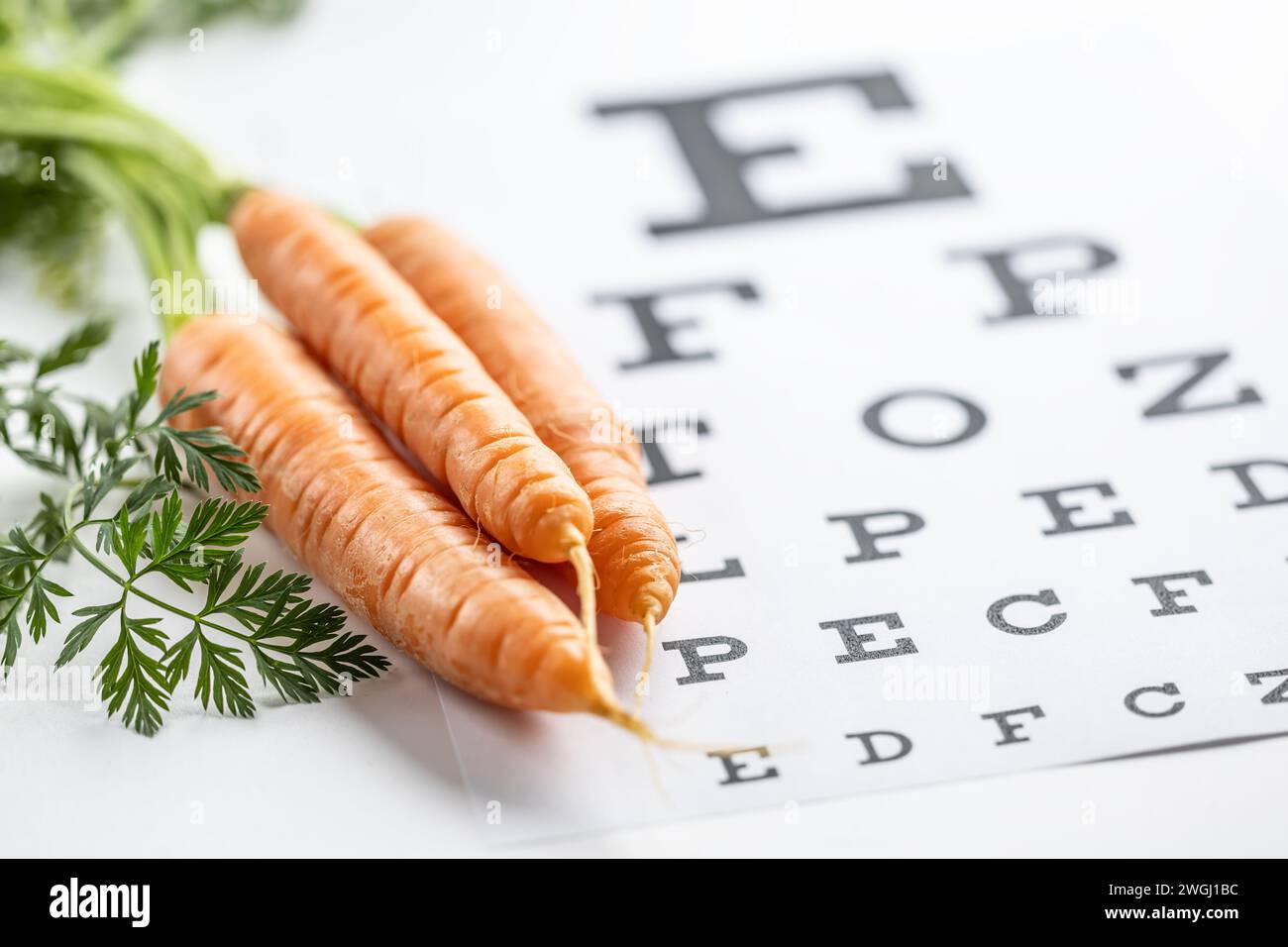 Frische Karotten als Vitamin-A-Quelle auf der Augentestkarte. Stockfoto