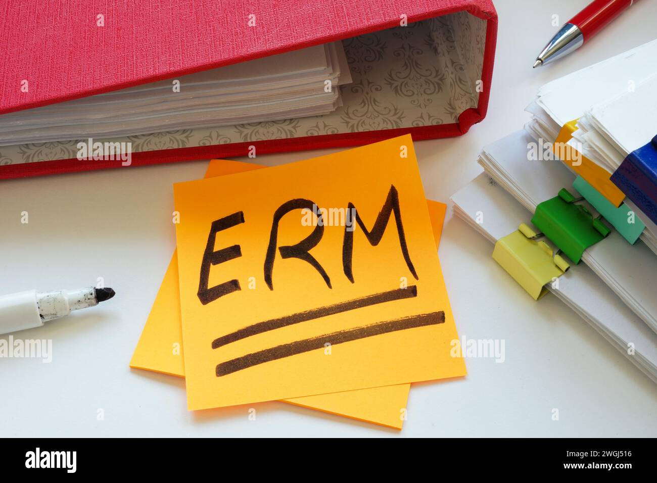 Ein Haftnotiz ERM Enterprise Risk Management mit einer Abkürzung neben einem Stapel Papiere. Stockfoto