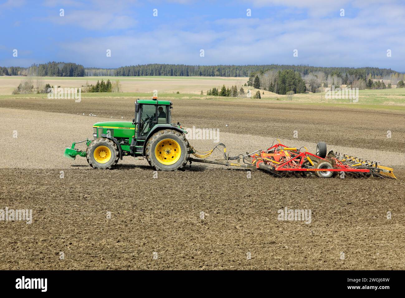 Arbeiten im Feld mit John Deere Traktor und Potila Magnum 800 Plus Saatbettgrubber an einem Frühlingstag. Salo, Finnland. Mai 2022. Stockfoto