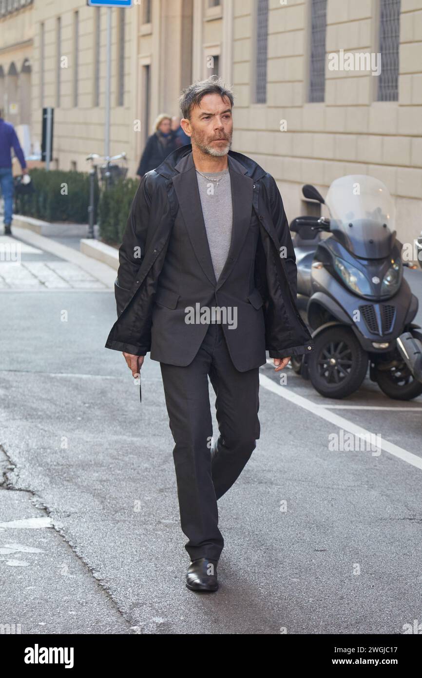 MAILAND, ITALIEN - 15. JANUAR 2024: Mann mit grauer Jacke und Hose vor Giorgio Armani Modenschau, Mailand Fashion Week Street Style Stockfoto