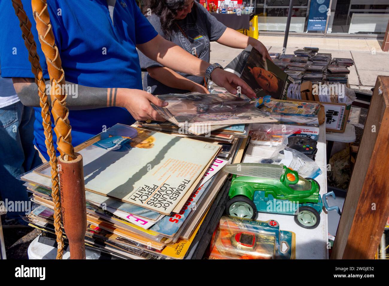 Zwei Leute suchen sich in Stapeln von Vinyl-33 1/3-Platten zum Verkauf an einem Straßenstand der Harlingen Market Days, Harlingen, Texas, USA. Stockfoto