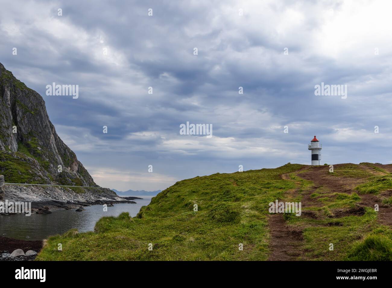 Ein Pfad führt zum Leuchtturm Borhella, einer einsamen Figur vor einem dramatischen Himmel, in Norwegens rauer Küstenlandschaft Stockfoto