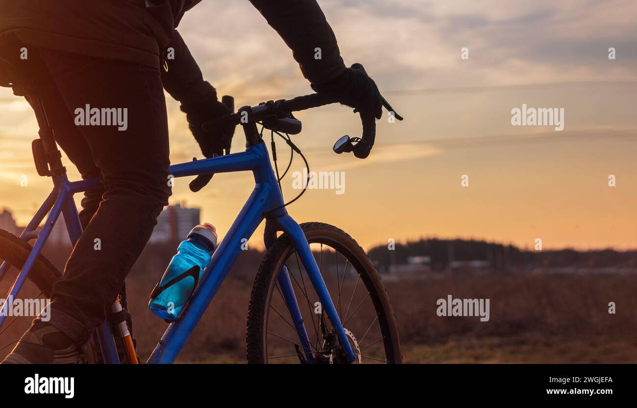 Radfahrer, der sein Fahrrad vor dem Hintergrund des Sonnenuntergangs fährt. Aktives Lifestyle- und Freizeitkonzept. Stockfoto