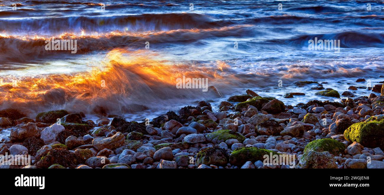 Golden Hour mit sonnendurchfluteter Welle am Kiesstrand am Clevedon Pier Beach, Vlevedon, Somerset, Großbritannien Stockfoto