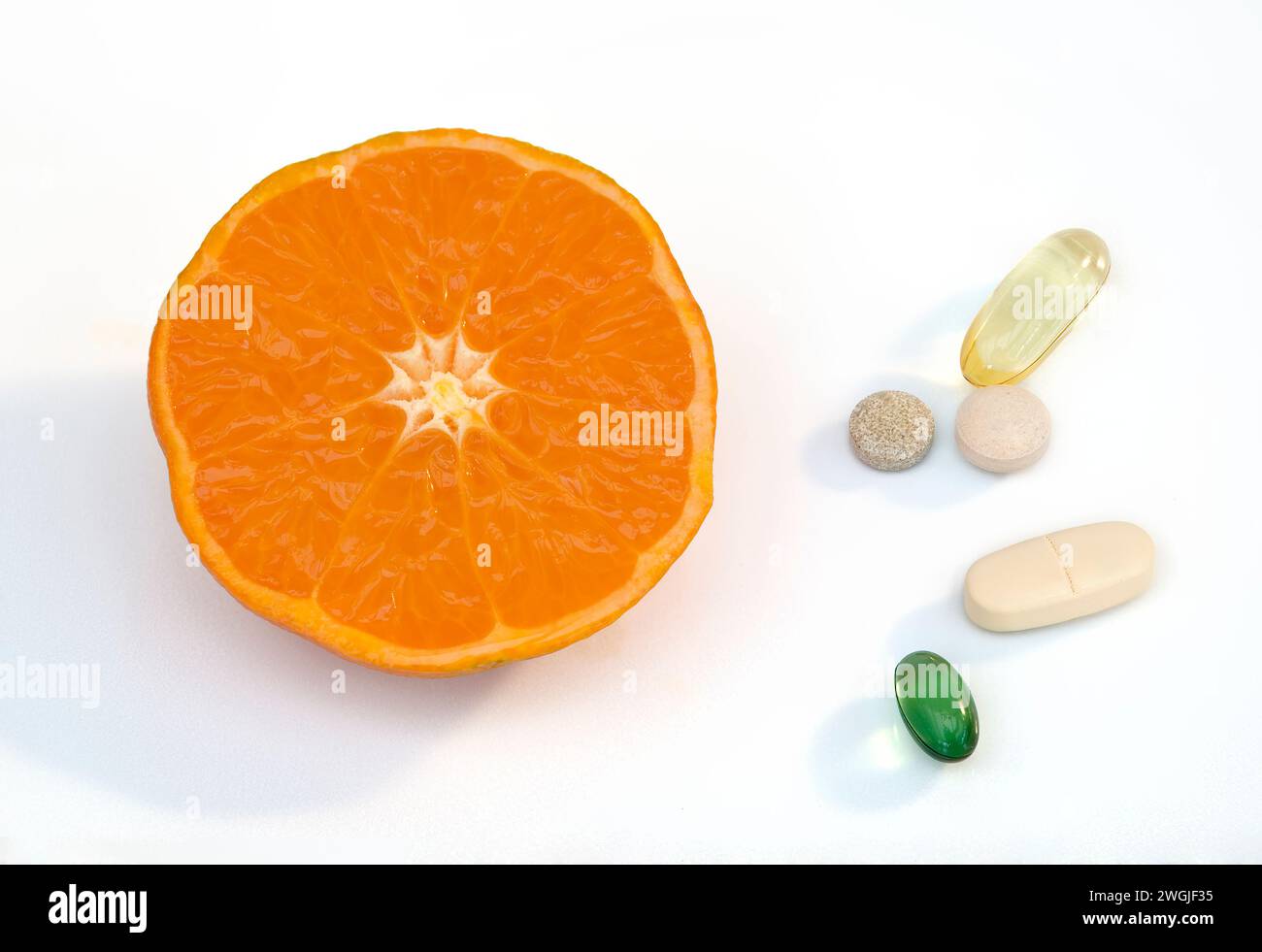 Studio-Aufnahme von Clementine-Orange-Hälfte, die eine Vielzahl von Mandarinen-Orange sind, auf weißem Hintergrund zusammen mit einer Mischung aus Vitamintablette dargestellt Stockfoto