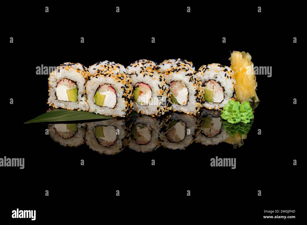 Sushi-Sets Uramaki, Kalifornien, Philadelphia, auf einem weißen Teller. Festliches Neujahrskonzept. Vor einem dunklen reflektierenden Hintergrund. Stockfoto