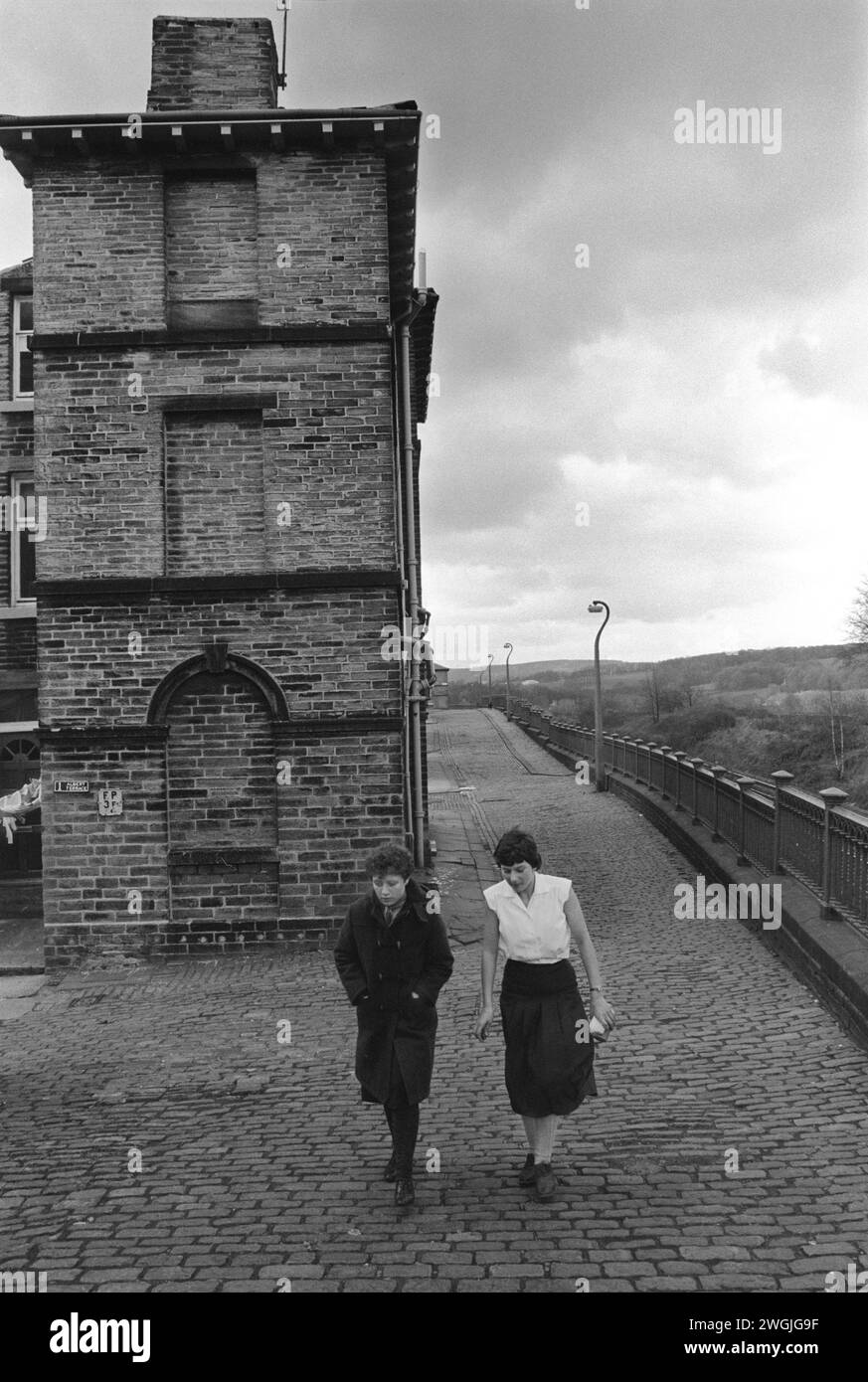 Saltaire Village Yorkshire 1980er Jahre Großbritannien. Junge Fabrikarbeiterinnen, die nach der Mittagspause wieder an die Arbeit gehen. 1 Albert Terrace, Saltaire ein Musterdorf, das vom Mühlenbesitzer Sir Titus Salt erbaut wurde. Salts Mill, benannt nach Sir Titus Salt, wurde 1986 nach 133 Jahren als Textilfabrik geschlossen. Salts Mill das Zentrum des vorbildlichen Industriedorfes wurde im 19. Jahrhundert auf den enormen Gewinnen aus Alpakasfasern errichtet. Saltaire bei Shipley Bradford West Yorkshire England 1981, heute UNESCO-Weltkulturerbe HOMER SYKES. Stockfoto