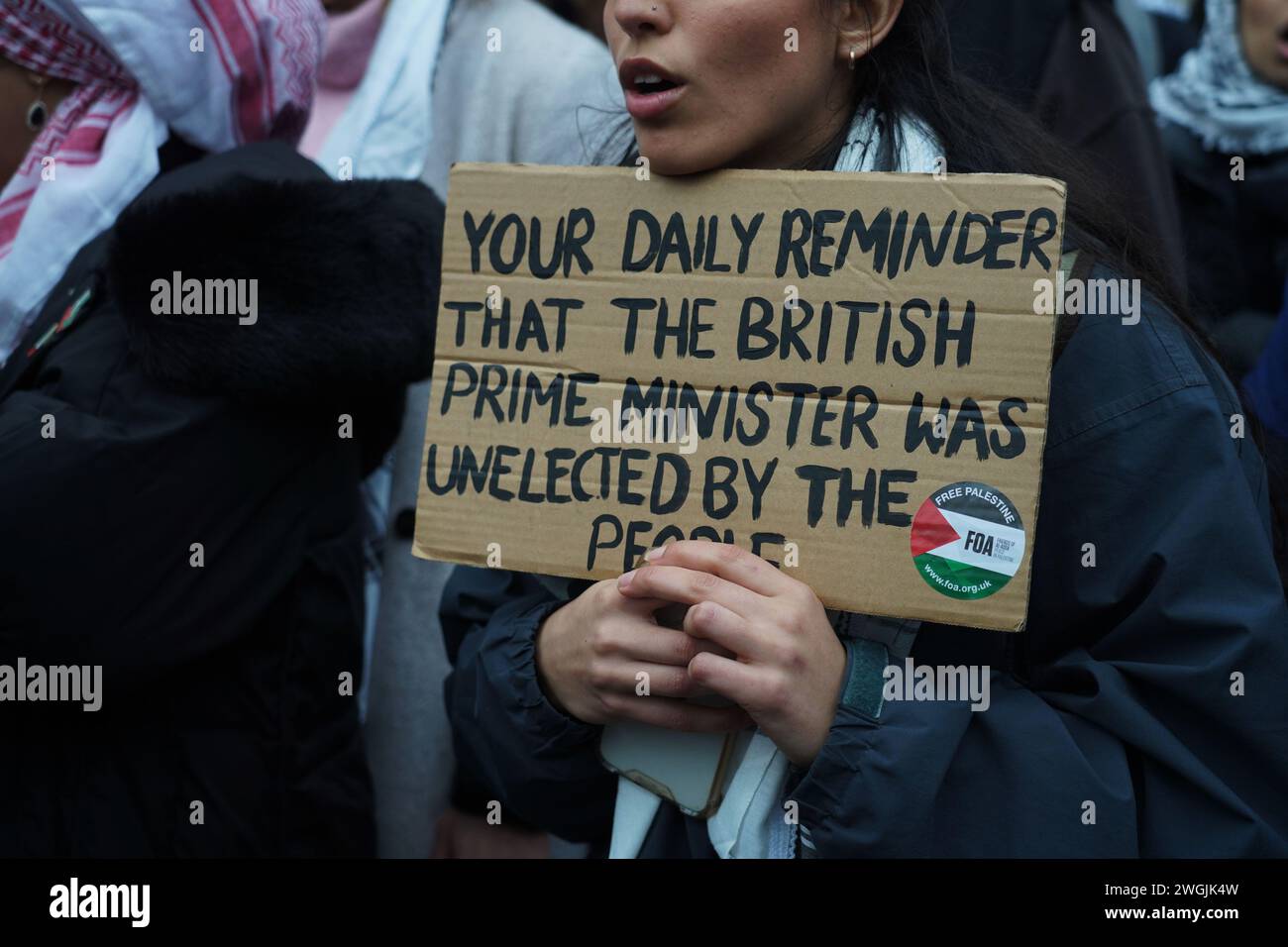 Eine Frau hält ein Plakat mit der Aufschrift, dass der britische Premierminister nicht gewählt wurde, als Hunderttausende auf dem Nationalmarsch für Palästina marschierten und einen Waffenstillstand forderten. Stockfoto