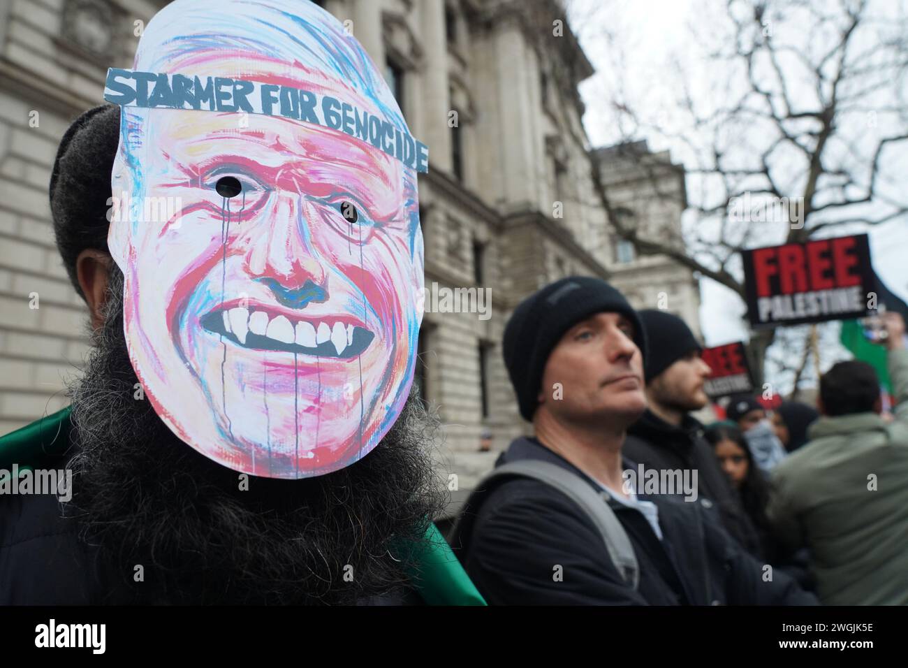 Ein Mann, der eine Keir Starmer Maske trägt und "Starmer für Völkermord" sagt, während Hunderttausende pro-palästinenser sich in Whitehall versammeln. Stockfoto