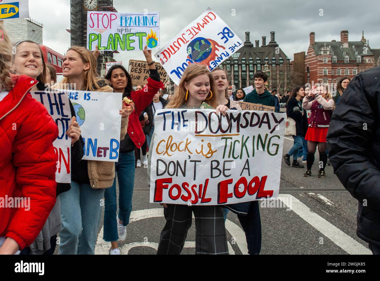 London. Klimaprotest. Mädchen mit Plakaten „Stop Fracking the Planet“, „Climate Justice“ und „The Doomsday Clock is ticking, don't be a Fossil Narr“. Stockfoto