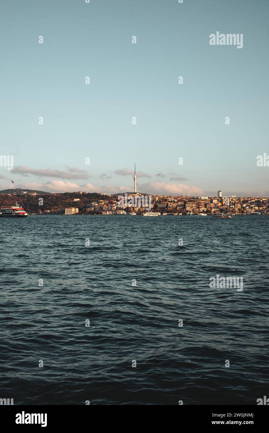 SOome-Boote segeln anmutig über den Ozean, inmitten einer malerischen Stadt und majestätischen Bergen während der bezaubernden Abenddämmerung in Istanbul, Türkei Stockfoto