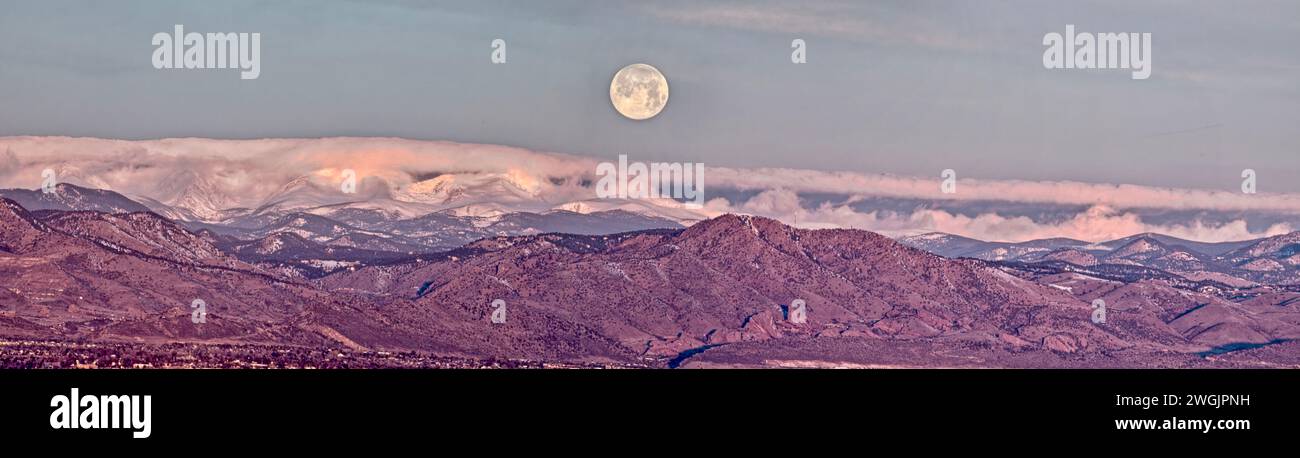 Der Wolfsmond steht kurz davor, hinter den Bergen der Colorado Front Range in Denver zu versinken. Stockfoto