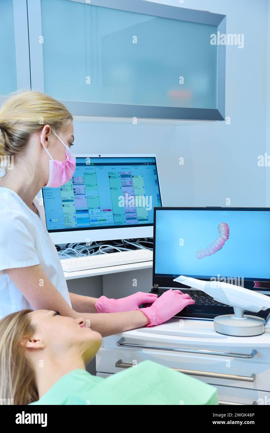 Zahnärztin und Patientin, die auf einem Laptop-Bildschirm einen 3D-Scan ansieht. Konzept für Gesundheitswesen und Stomatologie Stockfoto