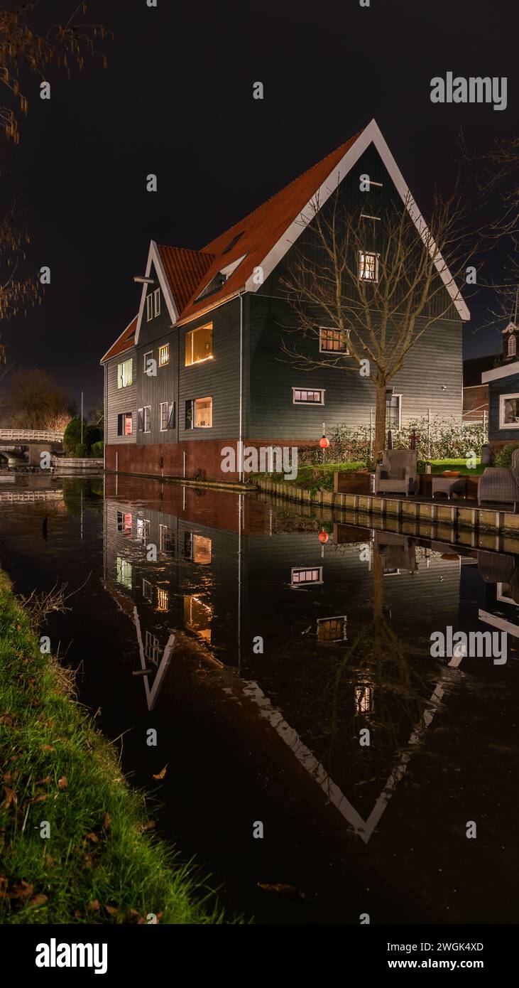 Großes Haus im malerischen Dorf de Rijp nördlich von Amsterdam spiegelt sich im Wasser. Dünne Eisschicht auf dem Wasser im Kanal. Stockfoto