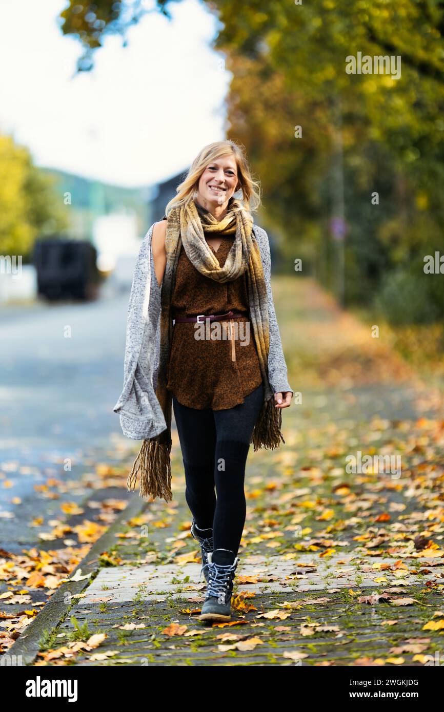 Mädchen Frau junger Vamp im gestrickten Stil mit blauen Stiefeln und schwarzen Leggings im Porträt in herbstlicher städtischer Lage.Street Art in einem kommerziellen Gebiet.Sie W Stockfoto