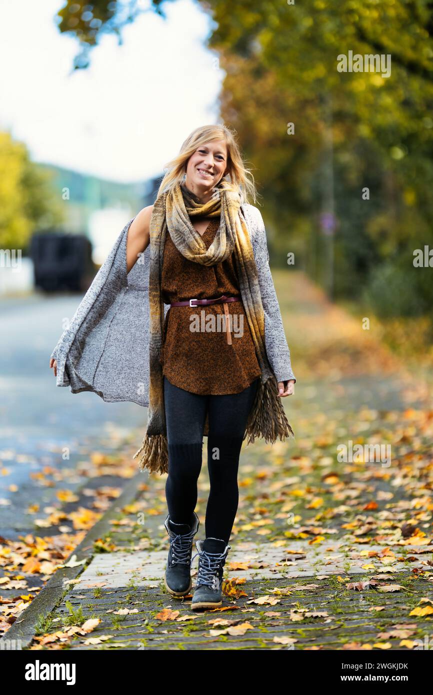 Mädchen Frau junger Vamp im gestrickten Stil mit blauen Stiefeln und schwarzen Leggings im Porträt in herbstlicher städtischer Lage.Street Art in einem kommerziellen Gebiet.Sie W Stockfoto