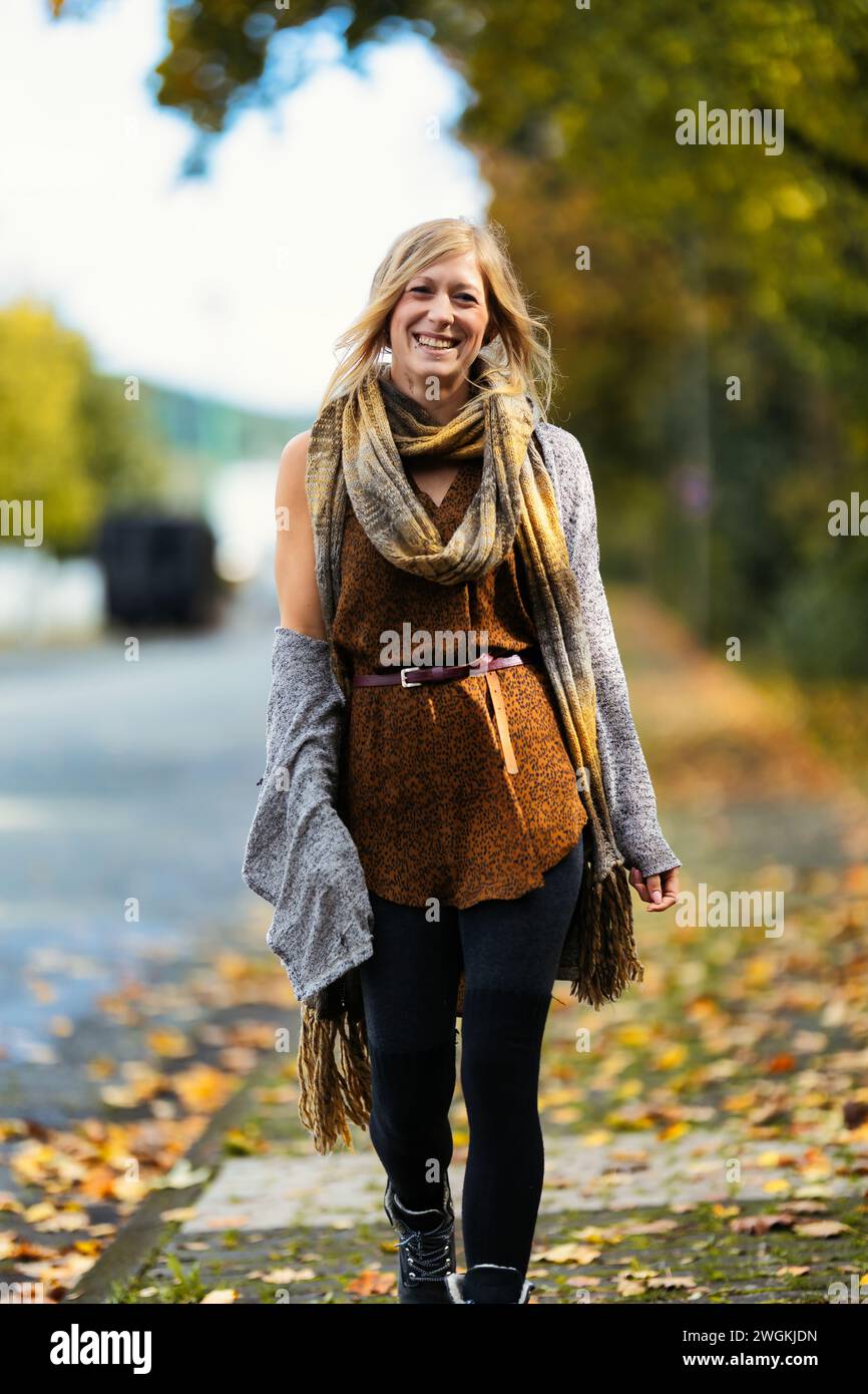 Mädchen Frau junger Vamp im gestrickten Stil mit blauen Stiefeln und schwarzen Leggings im Porträt in herbstlicher städtischer Lage.Street Art in einem kommerziellen Gebiet.Sie W Stockfoto