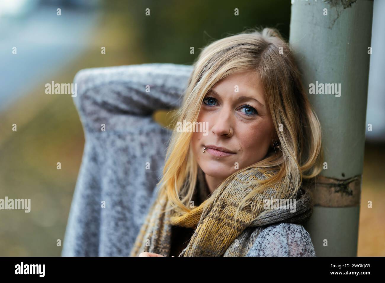 Mädchen Frau junger Vamp im gestrickten Stil mit blauen Stiefeln und schwarzen Leggings im Porträt in herbstlicher städtischer Lage.Street Art in einem kommerziellen Gebiet.Sie W Stockfoto