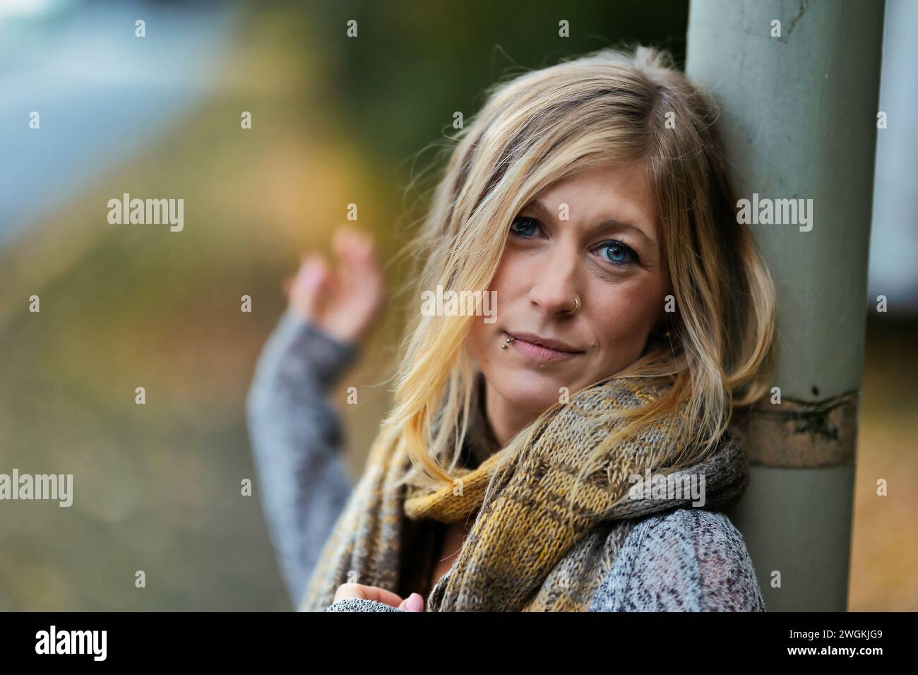 Mädchen Frau junger Vamp im gestrickten Stil mit blauen Stiefeln und schwarzen Leggings im Porträt in herbstlicher städtischer Lage.Street Art in einem kommerziellen Gebiet.Sie W Stockfoto