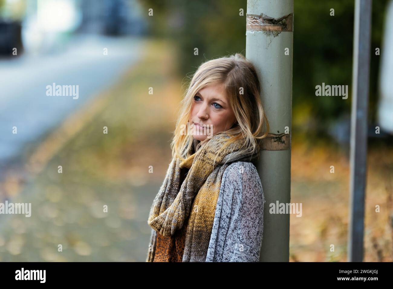 Mädchen Frau junger Vamp im gestrickten Stil mit blauen Stiefeln und schwarzen Leggings im Porträt in herbstlicher städtischer Lage.Street Art in einem kommerziellen Gebiet.Sie W Stockfoto