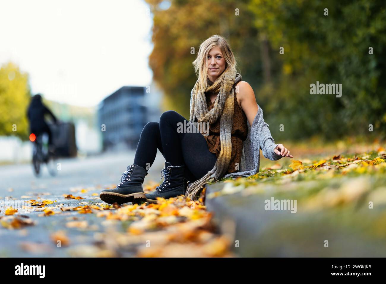 Mädchen Frau junger Vamp im gestrickten Stil mit blauen Stiefeln und schwarzen Leggings im Porträt in herbstlicher städtischer Lage.Street Art in einem kommerziellen Gebiet.Sie W Stockfoto