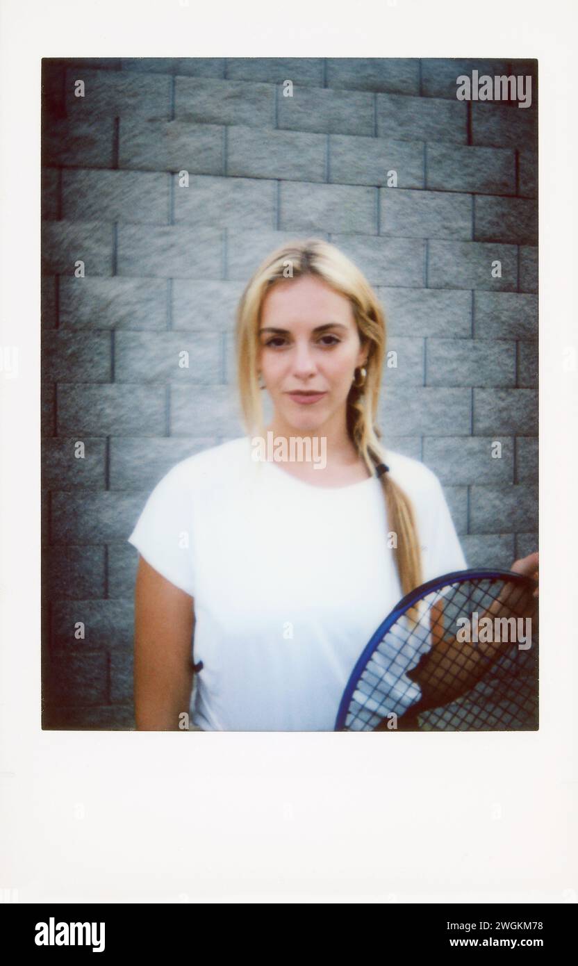 Porträt einer jungen Frau mit Tennisschläger vor einer Backsteinmauer, Retro-Ton. Stockfoto