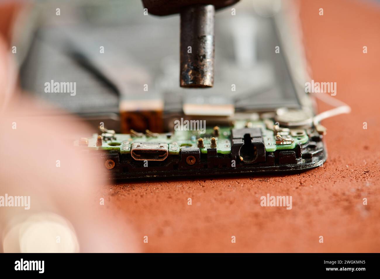 Nahaufnahme des zerlegten, defekten Mobiltelefons auf dem Tisch während der Wartung in der Werkstatt Stockfoto