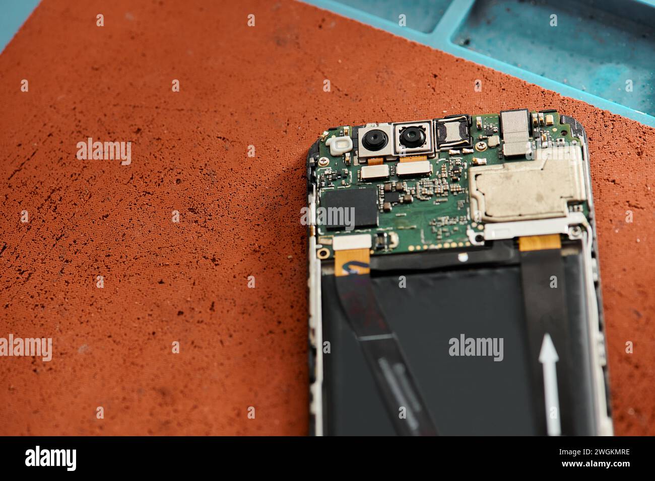 Draufsicht auf zerlegtes, kaputtes Mobiltelefon auf dem Tisch in moderner Werkstatt, Gerätereparatur Stockfoto