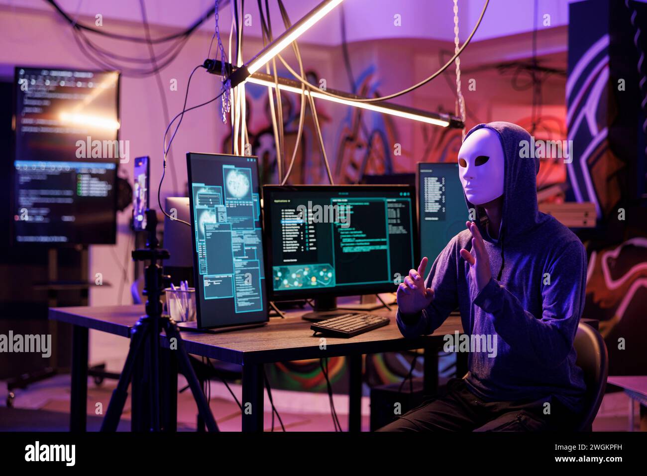 Hacker in anonymer Maske, die Videos mit Online-Betrug auf dem Mobiltelefon aufnimmt, während er illegale Aktivitäten ausübt. Internet-Betrüger-Streaming-Bedrohung, um Geld und Datenschutzinformationen zu erhalten Stockfoto