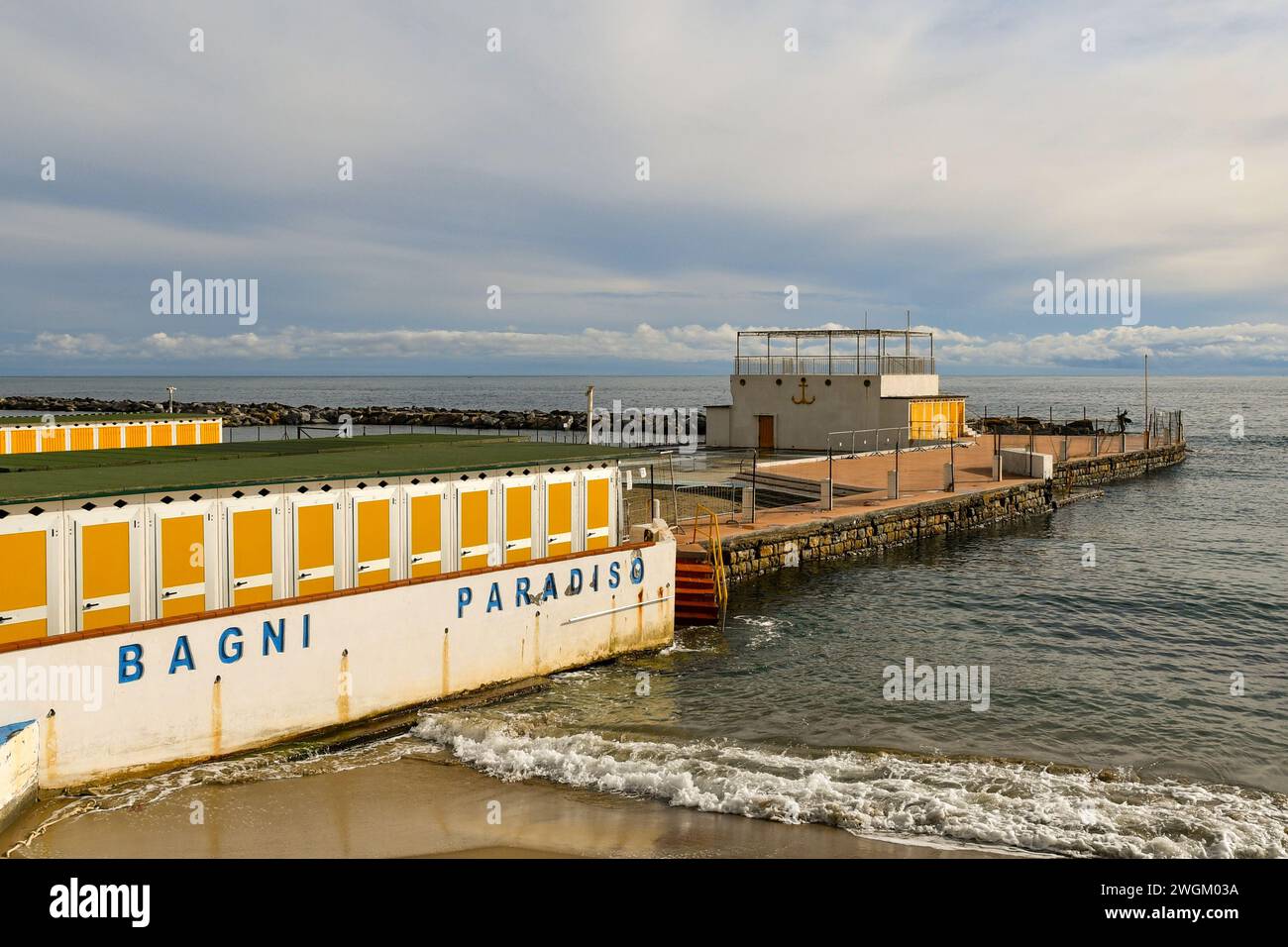 Erhöhter Blick auf den leeren Strand in der Nebensaison mit einer Reihe von Hütten und dem gemalten Schild des Badehauses 'Paradise Baths' im Winter, Sanremo, Ligurien Stockfoto