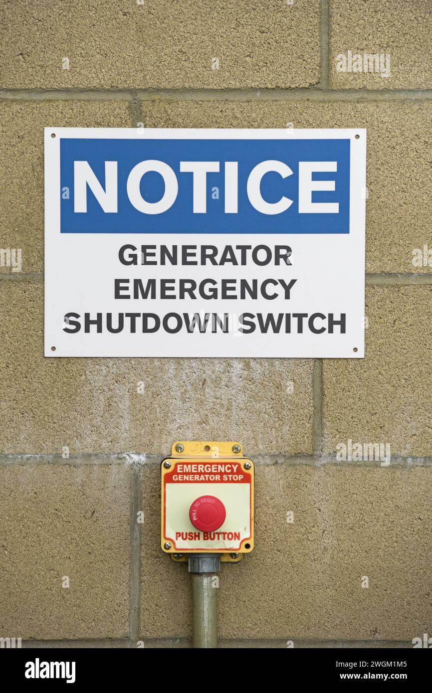 Notausschalter des Generators und Schilder an der Blockwand Stockfoto