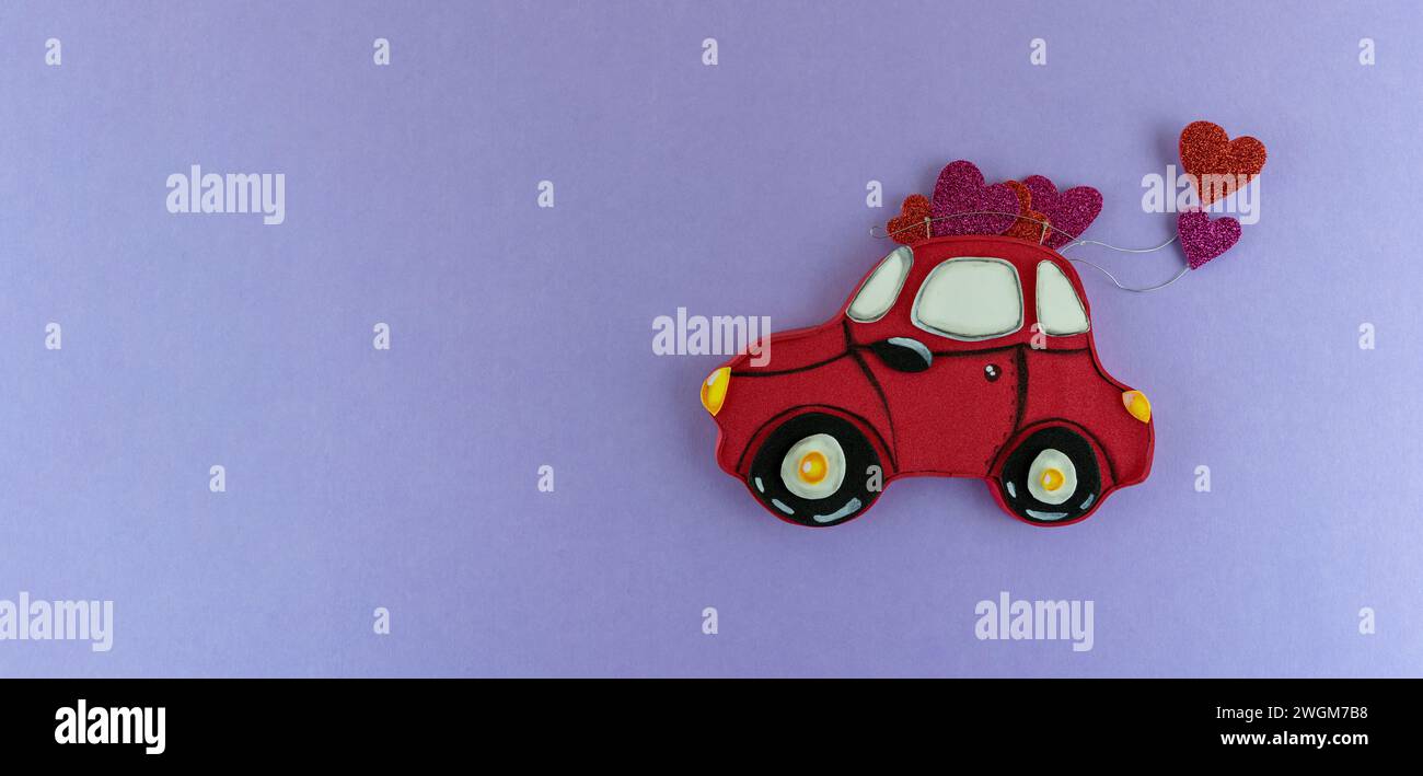 Handgefertigtes kleines rotes Auto mit Herzen auf dem Dach Stockfoto