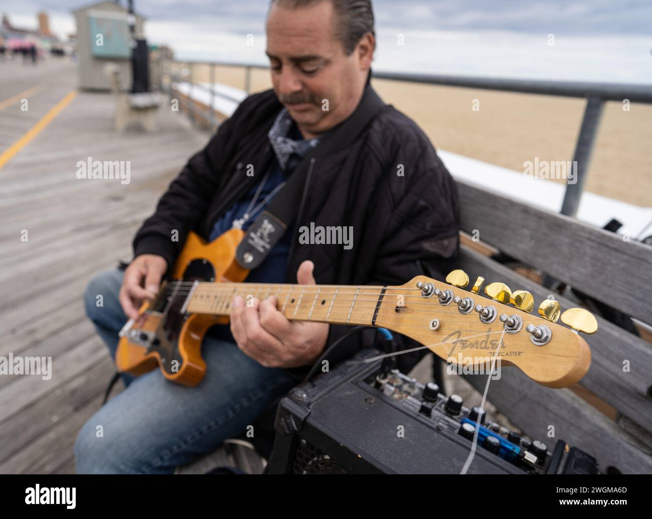 Harmoniert mit dem Rhythmus am Meer: Ein Mann spielt eine Fender-Gitarre auf der Promenade des Asbury Park, wo Musik auf die Meeresbrise trifft. Stockfoto