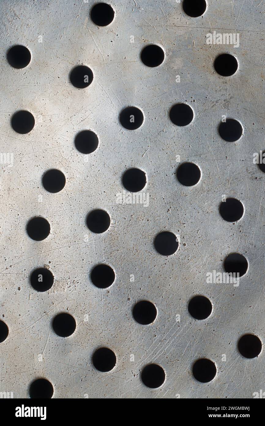 Abstrakt von alter schmutziger, zerkratzter Metalloberfläche mit runden Löchern im Hintergrund, Lochgitter oder perforiert auf grauer Aluminium- oder Silbertapete Stockfoto