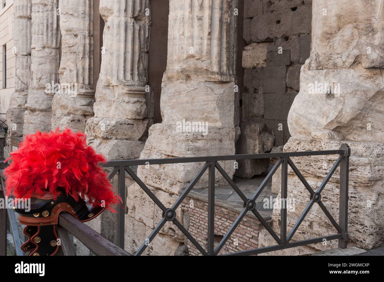 Kolonnade und Säulen von außen des Hadrian-Tempels mit Helm und hellroten Federn auf dem Geländer auf der Straße Rom, Kolonnade des Adriantempels Stockfoto
