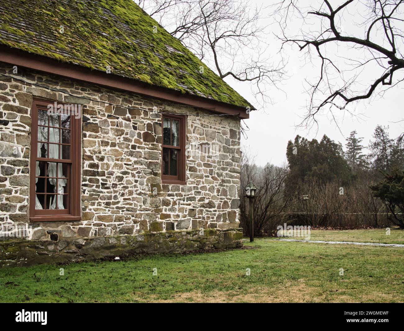 Altes Steinhaus mit moosigem Dach und knorrigem Baumzweig in der historischen Stadt Virginia. Stockfoto
