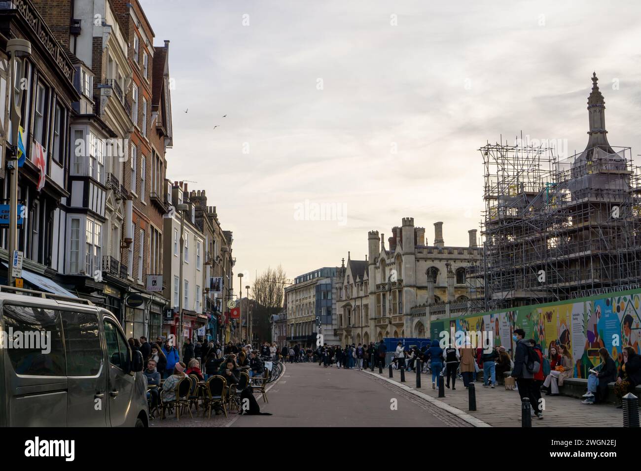 Touristen an einem bewölkten Nachmittag spazieren und sitzen vor Cafés in der Kings Parade in Cambridge, Großbritannien Stockfoto