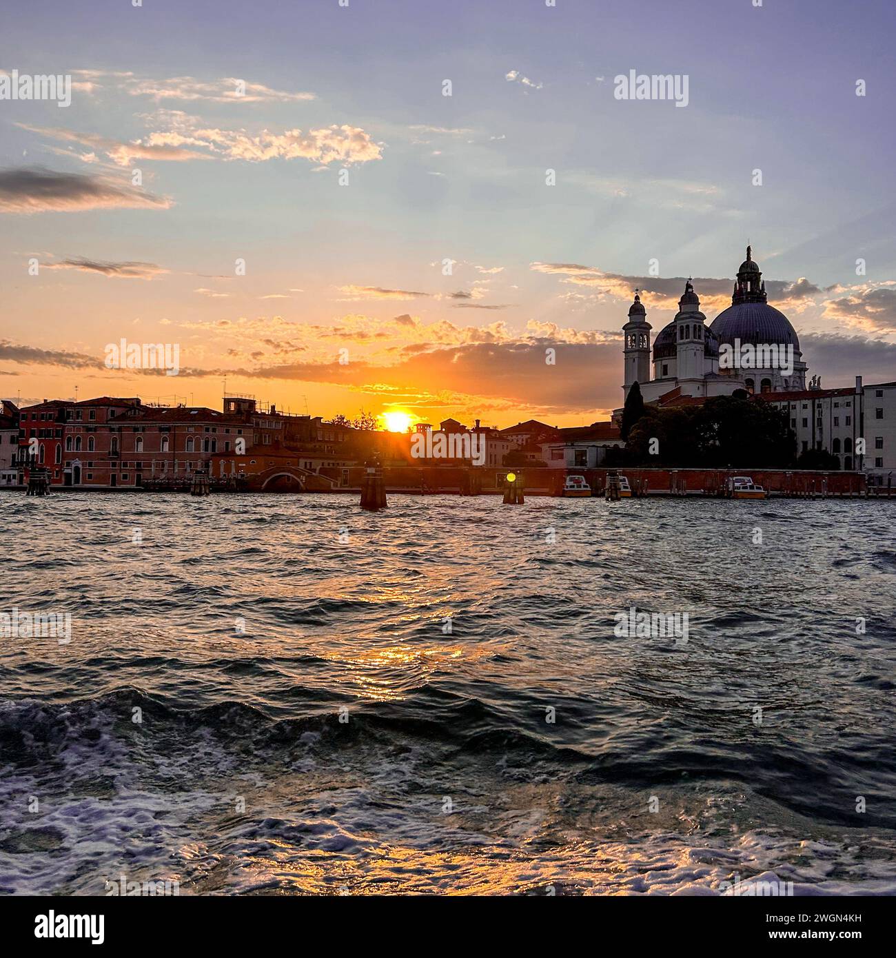 Eine atemberaubende aussicht entfaltet sich, während die Sonne unter dem Horizont eintaucht und einen goldenen Glanz über die zeitlose Schönheit Venedigs wirft und den Himmel mit Farbtönen übermalt Stockfoto