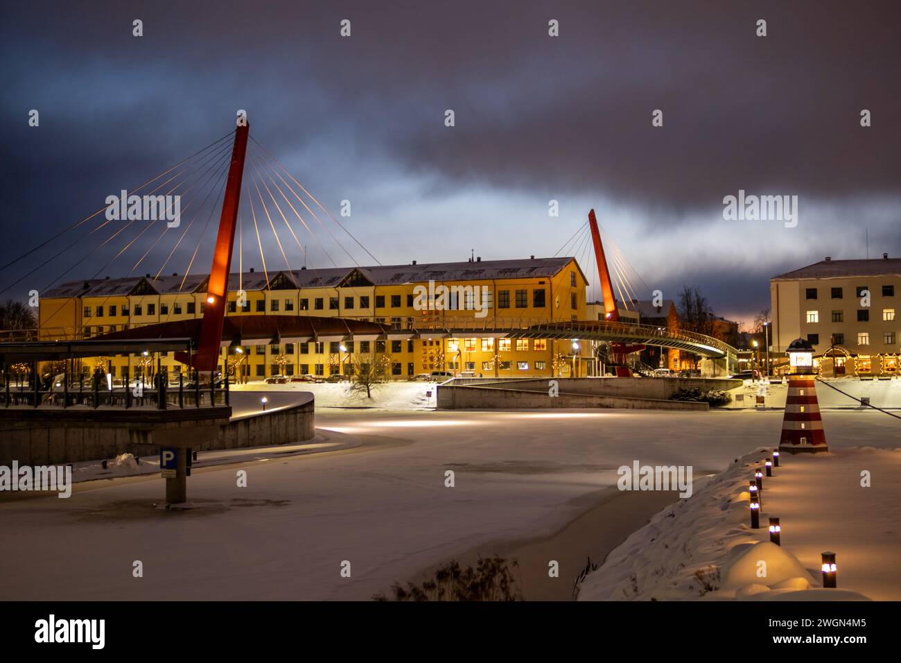 Im Herzen von Jelgava flüstert der Winter sein Schlaflied und malt die Stadt in schattigen Schneeschatten, während die Brücke als zeitloser Wächter steht. Stockfoto