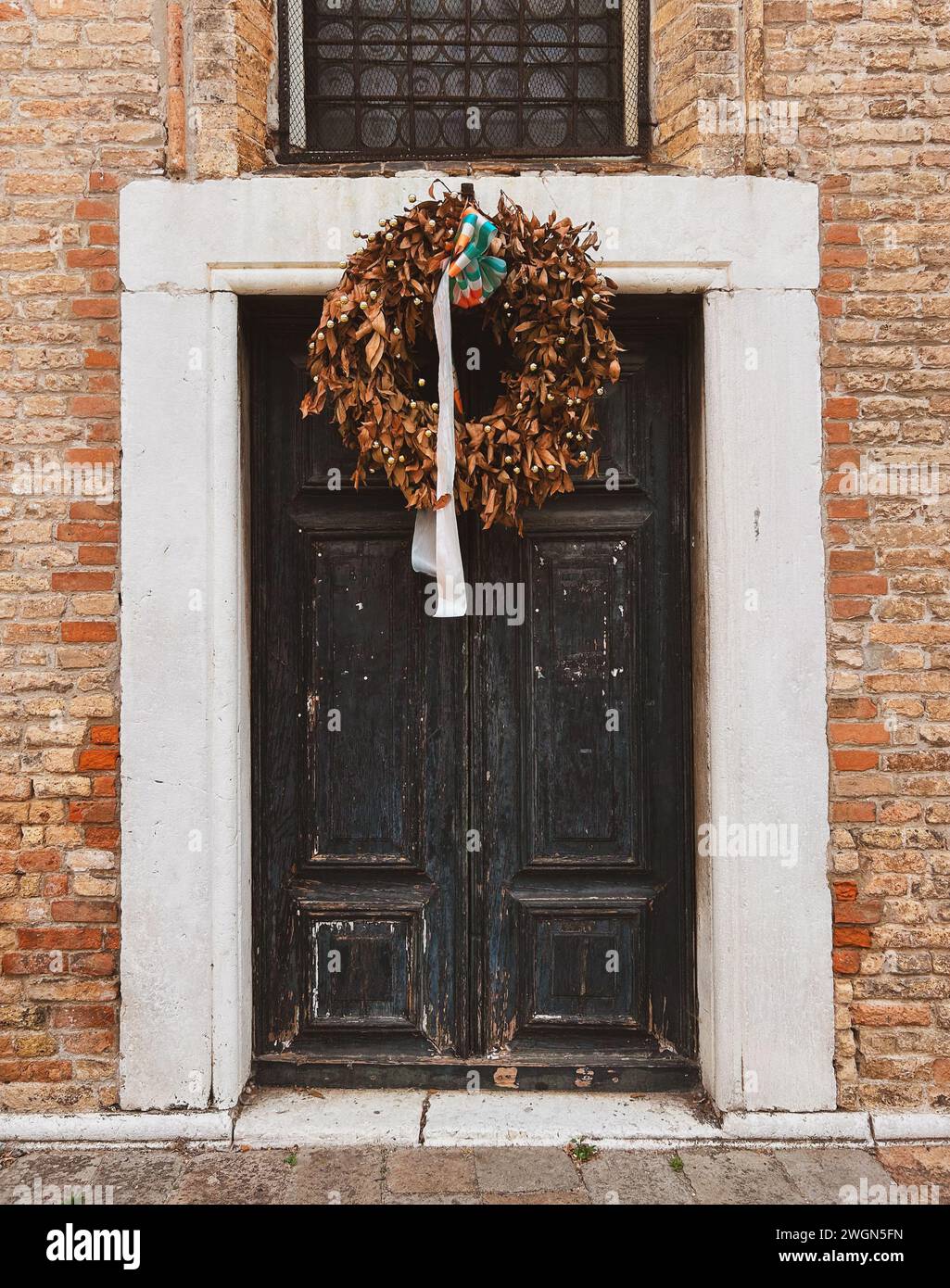 Ein Blick in die venezianische Geschichte: Diese verwitterte Holztür in Venedig flüstert Geschichten vergangener Epochen und lädt Sie ein, in eine Welt der zeitlosen Ele zu treten Stockfoto