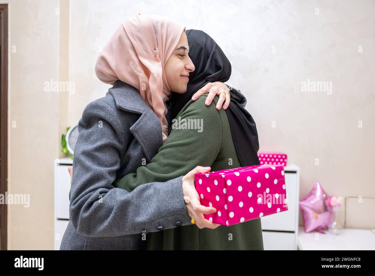muslimische Tochter umarmt und schenkt ihre Mutter Stockfoto muslimische Tochter umarmt und schenkt ihre Mutter Stockfoto