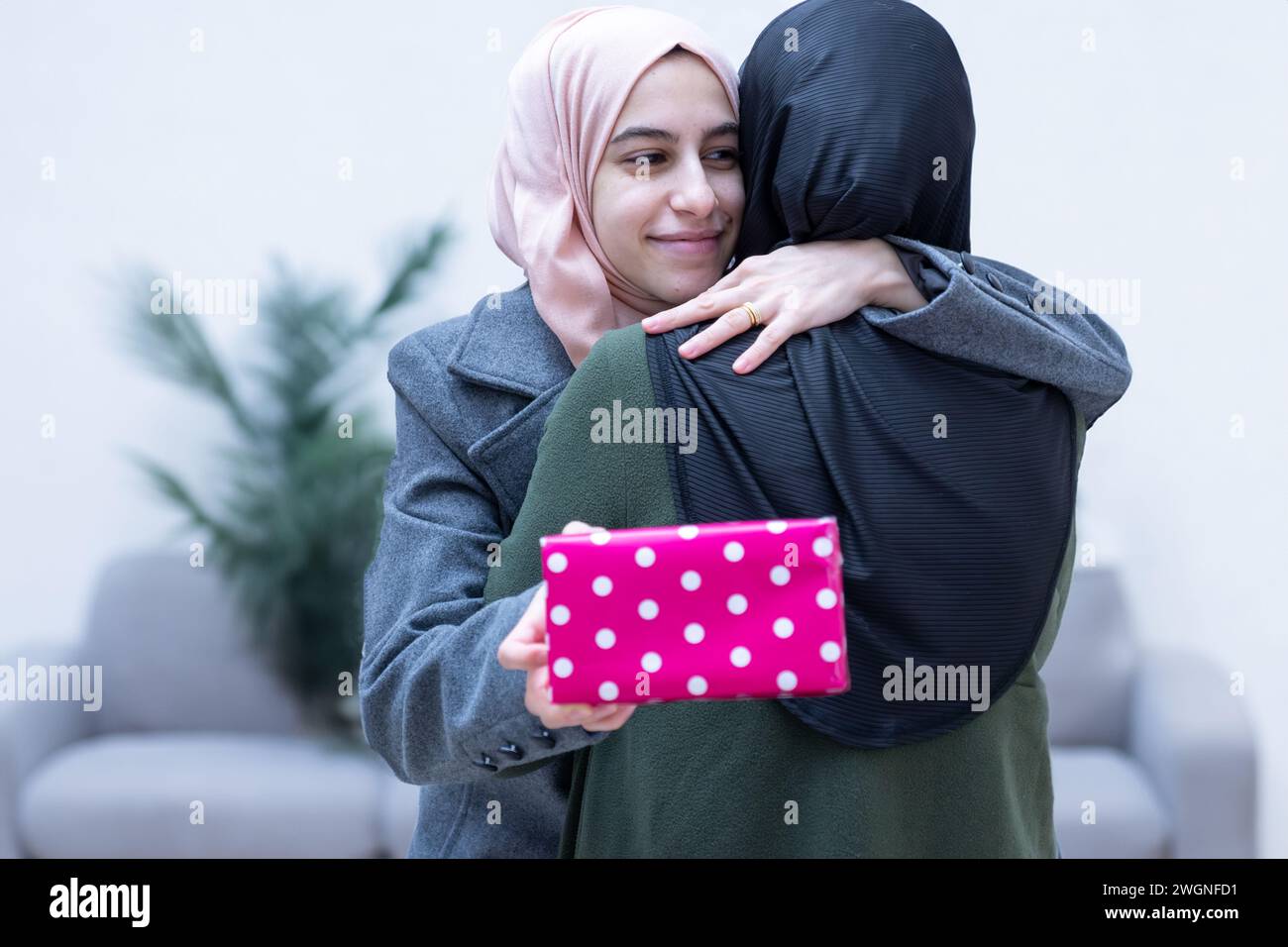 muslimische Tochter umarmt und schenkt ihre Mutter Stockfoto muslimische Tochter umarmt und schenkt ihre Mutter Stockfoto