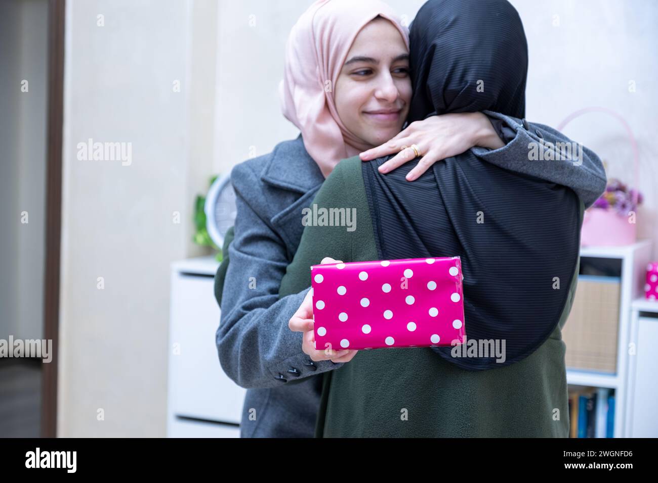 muslimische Tochter umarmt und schenkt ihre Mutter Stockfoto muslimische Tochter umarmt und schenkt ihre Mutter Stockfoto