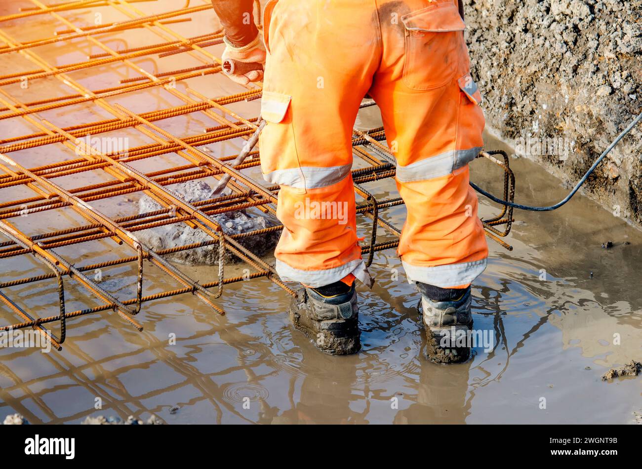 Der Baumeister verwendet einen elektrischen Bremser, um Beton von der Oberseite des Stapels zu brechen, um den Bewehrungskäfig darauf zu montieren Stockfoto